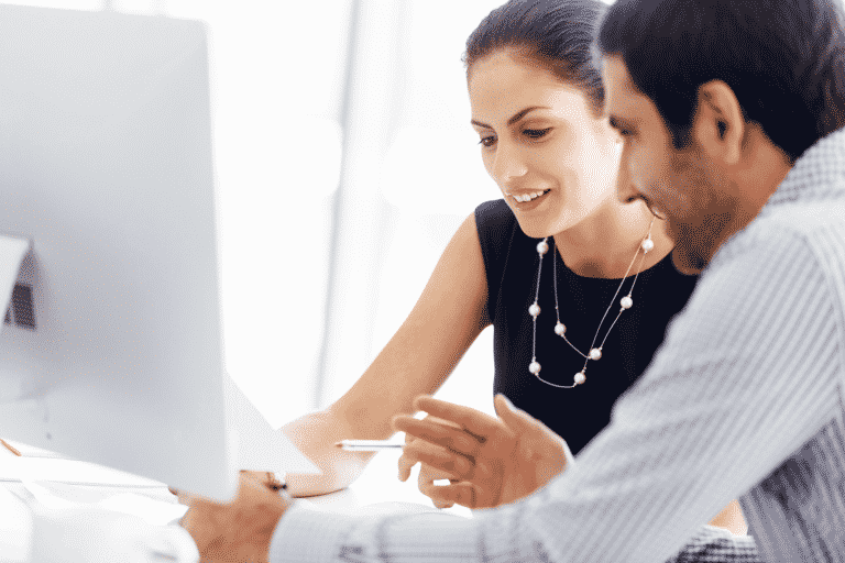 Foto van twee collega's die samen iets bekijken en bespreken