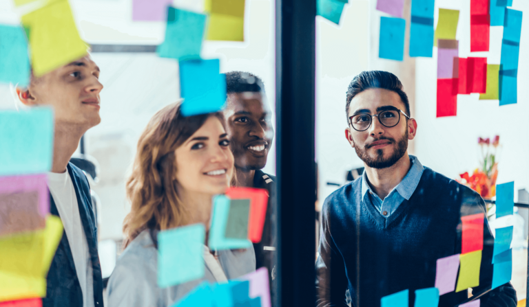 Foto van personen temidden van een glazen wand met post-its