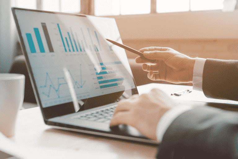 Foto met handen van iemand die laptop bedient, met een hand typt en de andere aanwijst