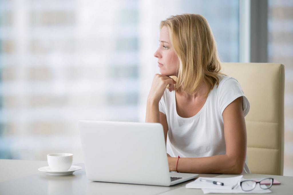 Foto van een vrouw achter laptop die nadenkt over datageletterdheid