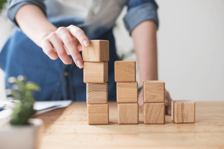 Foto van een persoon die met zijn vingers blokken aan het stapelen is.