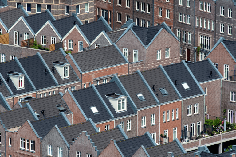 Deze afbeelding toont een dicht cluster van bakstenen woonhuizen met schuine daken, dakramen en een consistente architecturale stijl.